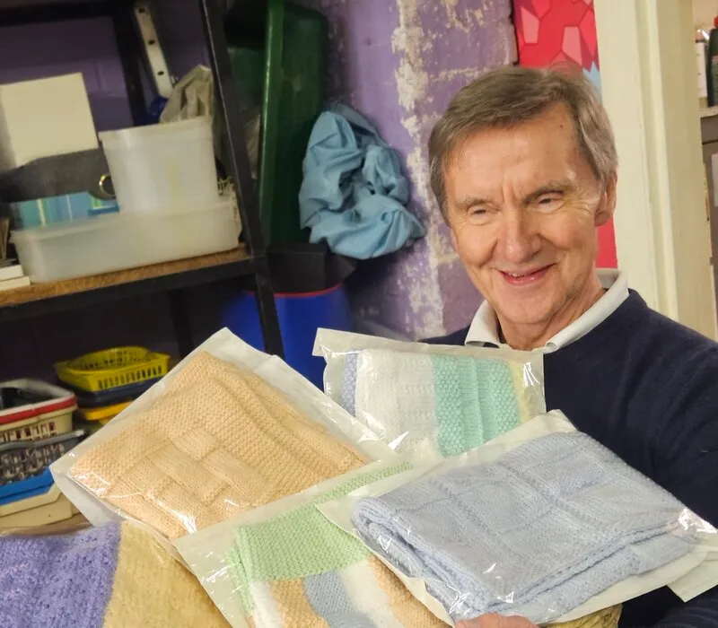 A volunteer smiling while sorting donated towels and textiles in the store